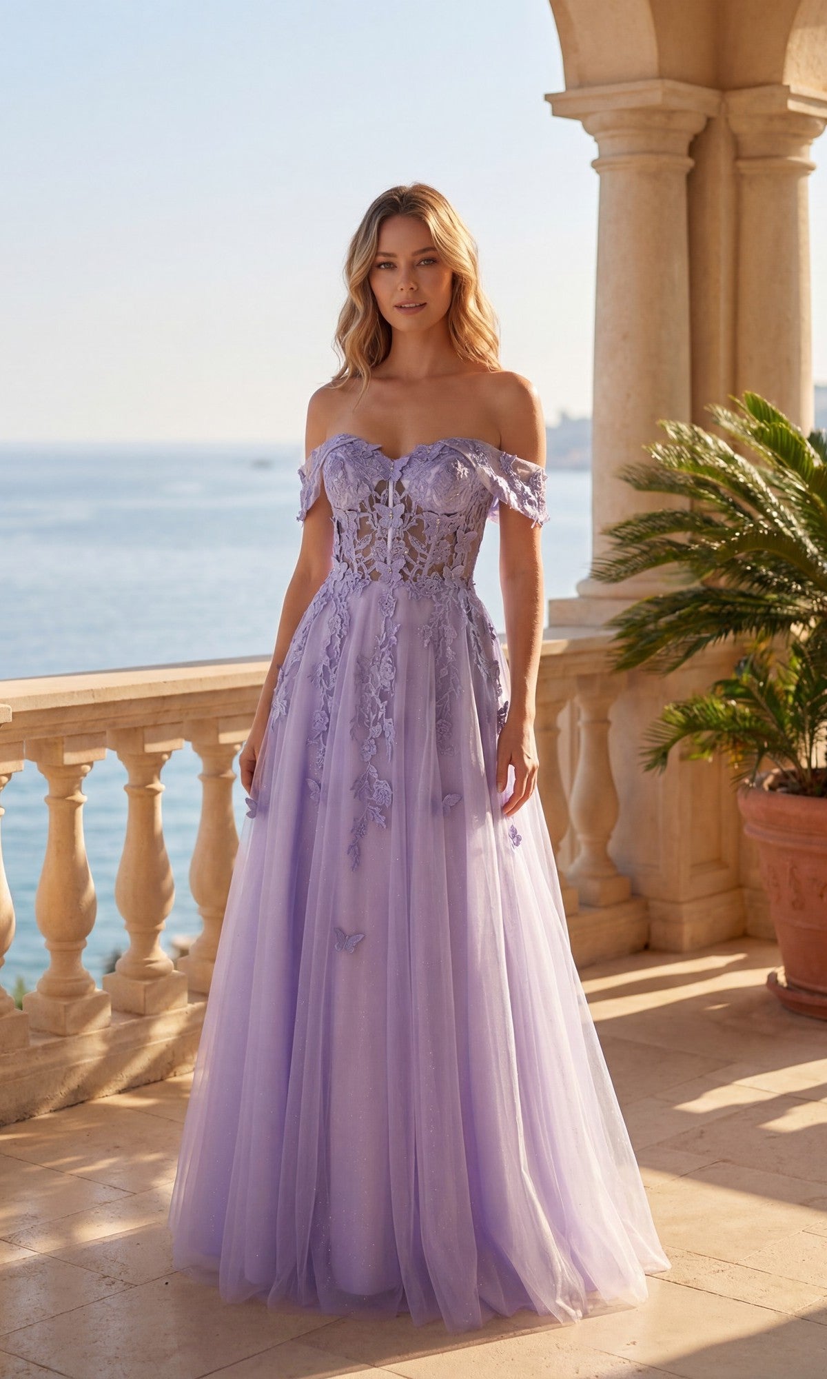 A woman stands on a terrace by the sea, wearing the Long Prom Dress: Chicas C350 in lilac, featuring an off-the-shoulder A-line silhouette with floral accents and a delicate corset-style bodice.